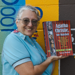 Agatha Christie She Watched Series 3 Teresa Peschel holding up a copy of jer book Agatha Christie, She Watched