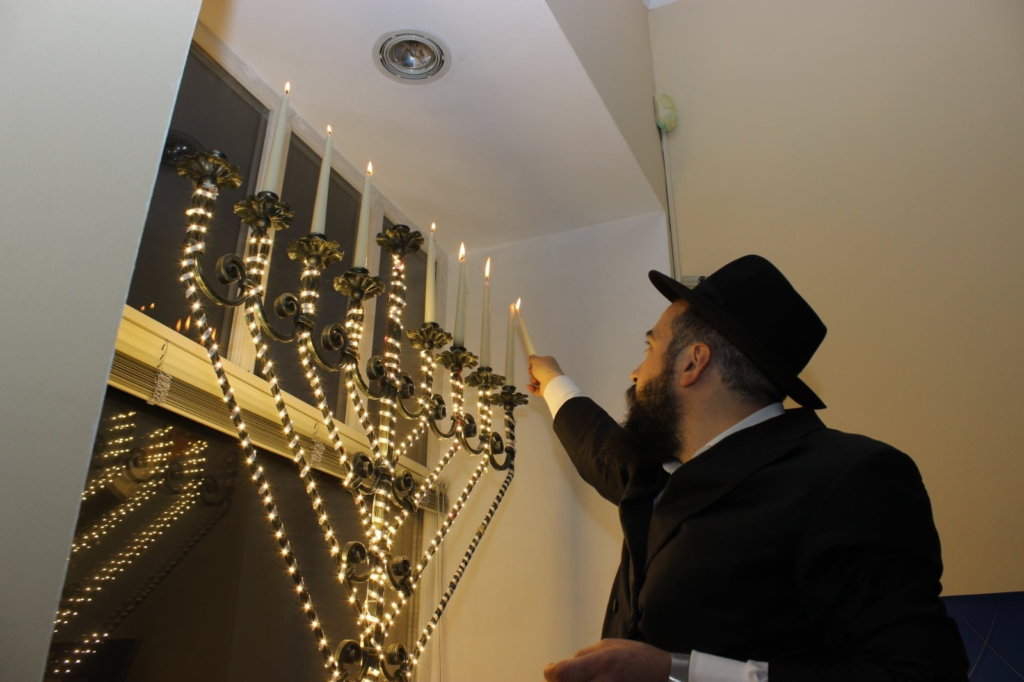 Rabbi Mendel Cohen lighting the menorah in the temple of Mariupol. 